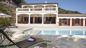 Ein Poolbereich mit Liegestühlen, einem Buch und Blick auf ein Gebäude mit Pool.