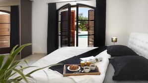 Ein Hotelzimmer mit Bett, Frühstückswagen und Blick auf einen Pool.