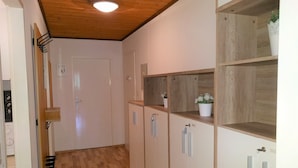 Un couloir doté d’un plancher en bois, de meubles blancs et d’un plafond avec des poutres apparentes.