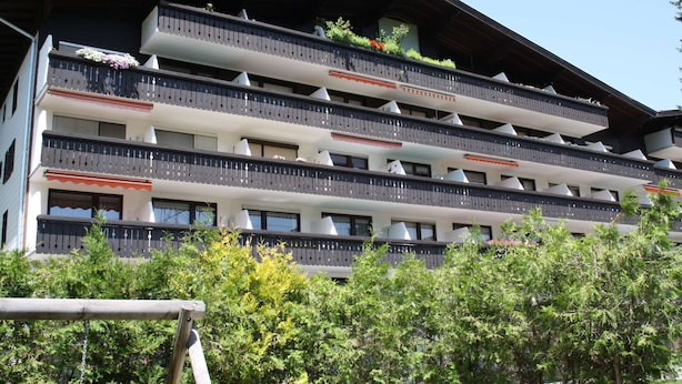 Un hôtel à plusieurs étages doté de balcons, chacun ayant un petit espace jardin.