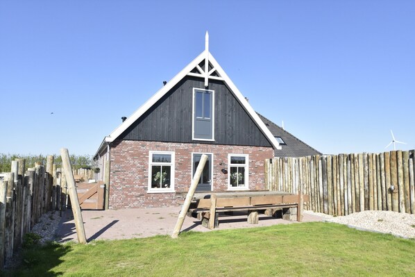 A single-story brick building with a dark roof and white trim, featuring two windows and a door. - Family Home in Rural Location near Coast of Noord-holland Province (Callantsoog)