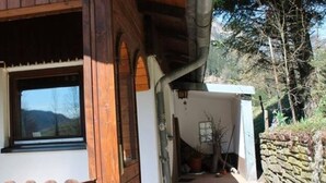 Ett trähus med en veranda, en stenmur och utsikt över det omgivande landskapet.