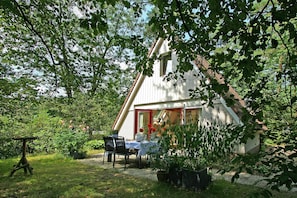A house with a dining area, a table, chairs, and potted plants.