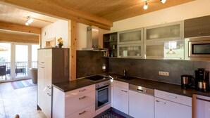 A modern kitchen with white cabinets, a stainless steel range, and a microwave. - Classic Chalet With Infrared Sauna (Murau)