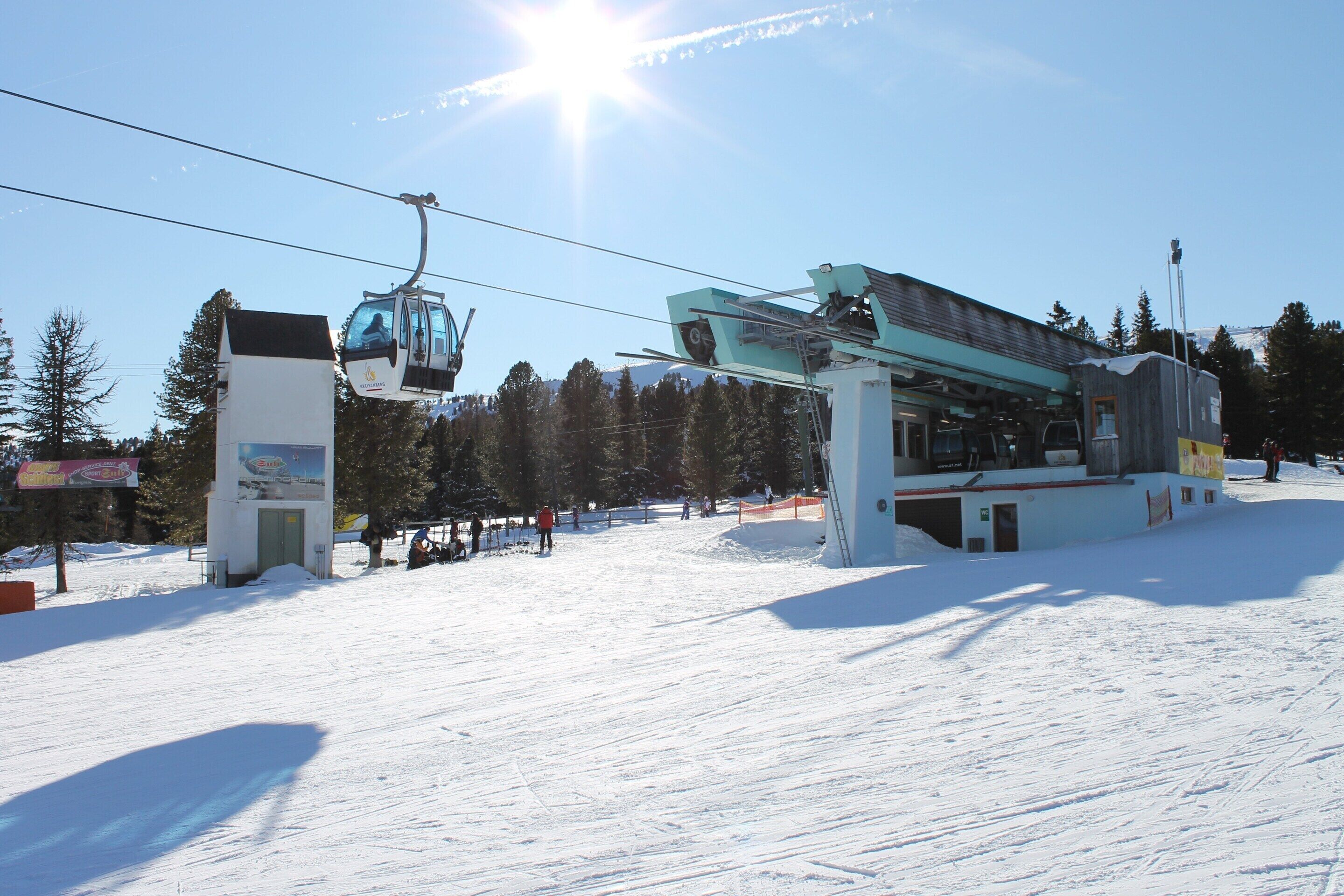 A ski lift with a cable car system, a snow-covered slope, and a mountain in the background.