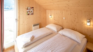 A wooden cabin room with two beds, a door to a balcony, and a wall-mounted light fixture. - Classic Chalet With Infrared Sauna (Murau)