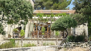 A stone building with a tiled roof, surrounded by trees and a metal fence. - Villa in Crillon-le-brave Near Mont Ventoux (Crillon-le-Brave)
