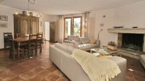 A living room with a sofa, a dining table with chairs, a fireplace, and a large window. - Villa in Crillon-le-brave Near Mont Ventoux (Crillon-le-Brave)