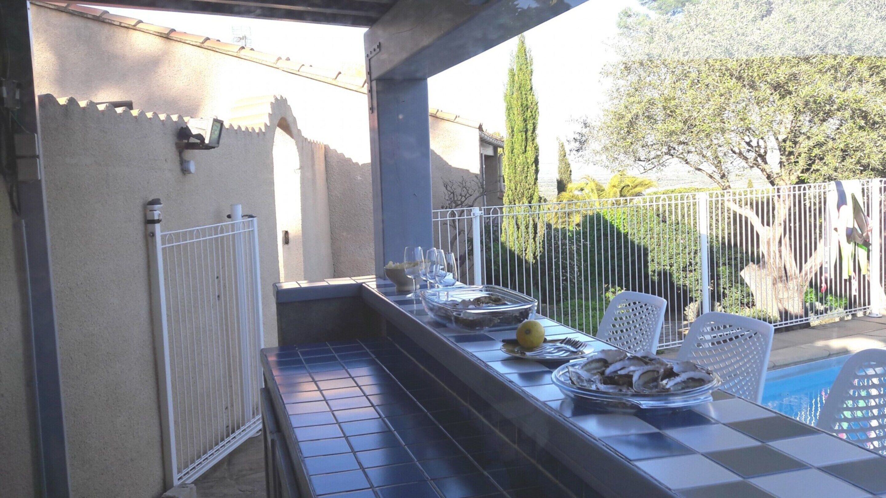 An outdoor dining area with a checkered table, chairs, and a metal fence.
