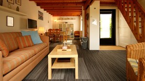 A cozy living room with a wooden ceiling, a sofa, a coffee table, and a staircase leading to another room. - Nice Holiday Home for 5 People, Within Walking Distance of the Beach (Burgh-Haamstede)
