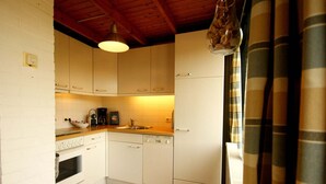 A compact kitchen with white cabinets, a built-in oven, a coffee maker, and a hanging light fixture. - Nice Holiday Home for 5 People, Within Walking Distance of the Beach (Burgh-Haamstede)