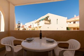 A balcony with a round table and two chairs, overlooking a building with balconies and plants. - Mare Verde 95 - One Bed (Costa Adeje)