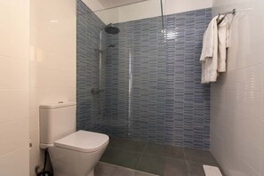 A bathroom with a toilet, a shower with a glass door, and a towel rack with towels. - Mare Verde 95 - One Bed (Costa Adeje)