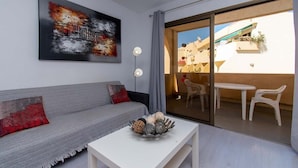 Ein modernes Wohnzimmer mit einem grauen Sofa, einem weißen Couchtisch und einem großen abstrakten Gemälde.