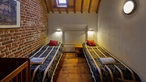 A cozy room with two beds, a wooden floor, a brick wall, a skylight, and a round light fixture. - Spacious Apartment near Town Center in Mesch (Eijsden)