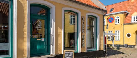 A yellow building with a green door and windows, labeled "Café ERO" and "ARC Guesthouse."