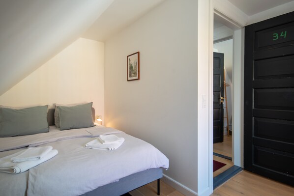 Un dormitorio con cama, almohadas y un cuadro en la pared.