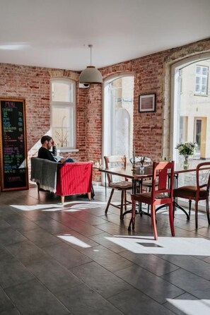 Un restaurante con paredes de ladrillo, ventanas amplias y una pizarra con el menú.