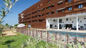 Ein mehrstöckiges Hotel mit Poolbereich, Außenbereich und überdachter Eingangszone.