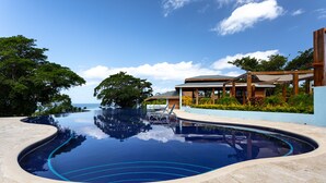 Ein Pool mit geschwungener Kante, umgeben von einer Steindeck und einer Holzpergola.