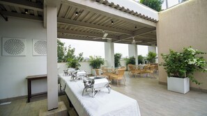 An outdoor patio with a covered seating area, a buffet table, and potted plants. - House of Backpackers (Jaipur)