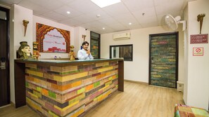A reception desk with a colorful wooden design, a sign for Palm Hospitality, and a no smoking sign on the wall. - House of Backpackers (Jaipur)
