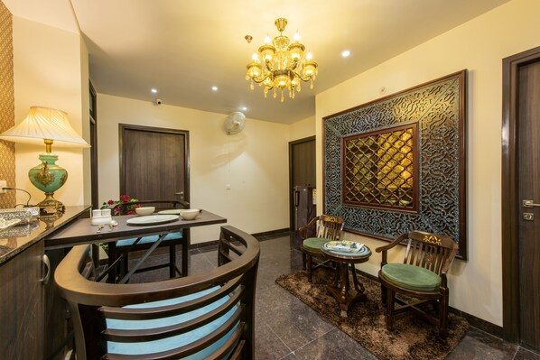 A dining area with a chandelier, a table with chairs, a decorative wall panel, and a door. - House of Backpackers (Jaipur)