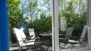 An outdoor patio with a table and four chairs, surrounded by trees. - Holiday Home Ameland Near North Sea Beach (Nes)