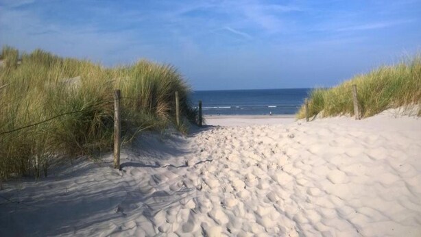 A sandy beach path leading to the ocean, flanked by grassy dunes and wooden posts. - Holiday Home Ameland Near North Sea Beach (Nes)
