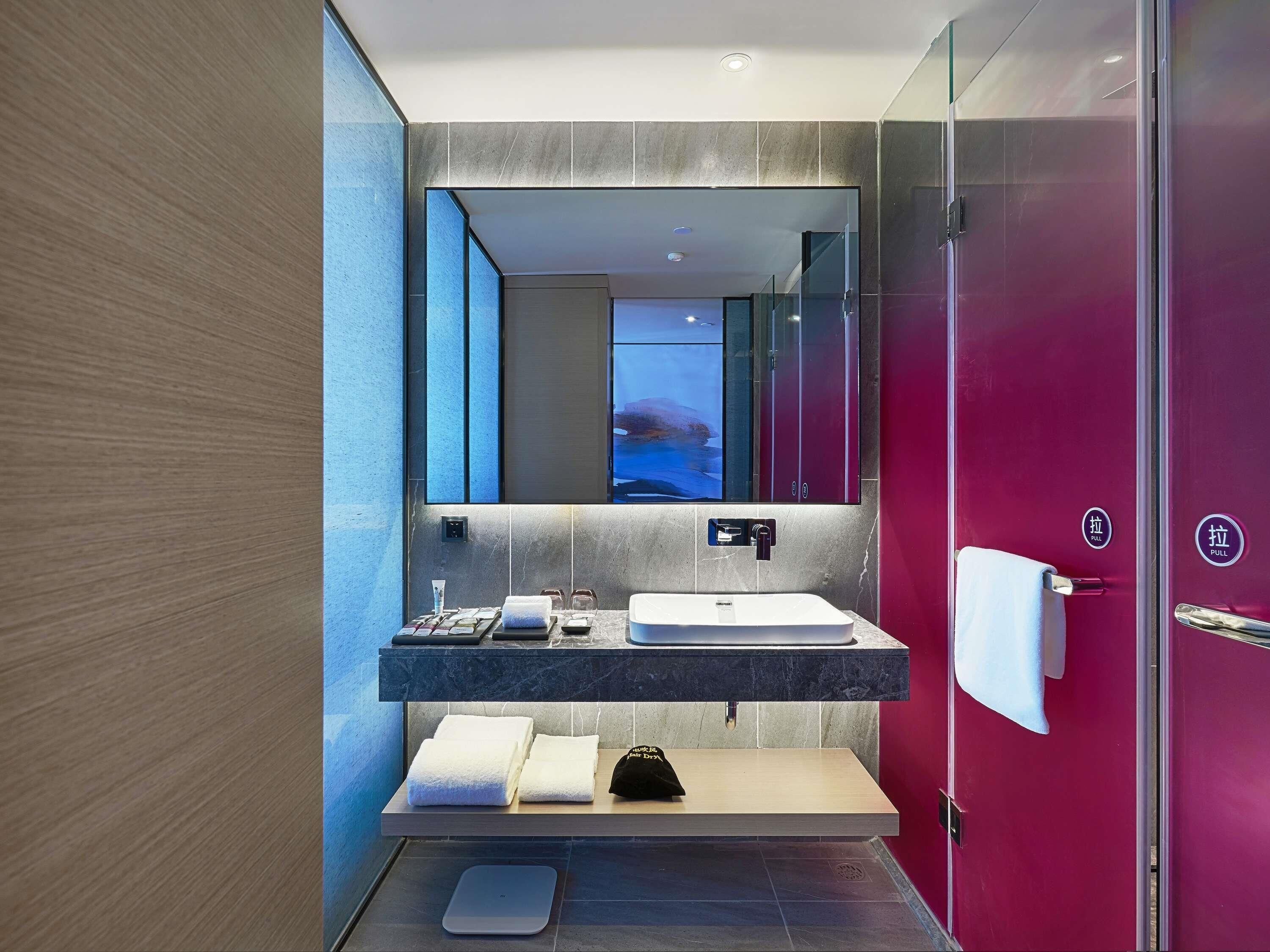 A modern bathroom with a large mirror, a sink, and a towel rack.