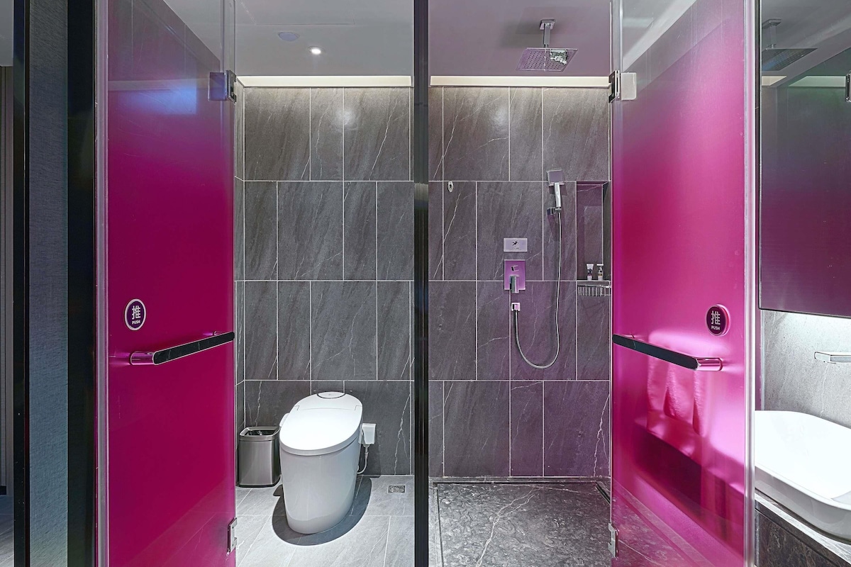 A modern bathroom with a glass shower enclosure, a toilet, and a sink.