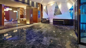 Un lobby moderno con mostrador de recepción, zona de estar y una amplia pantalla digital.