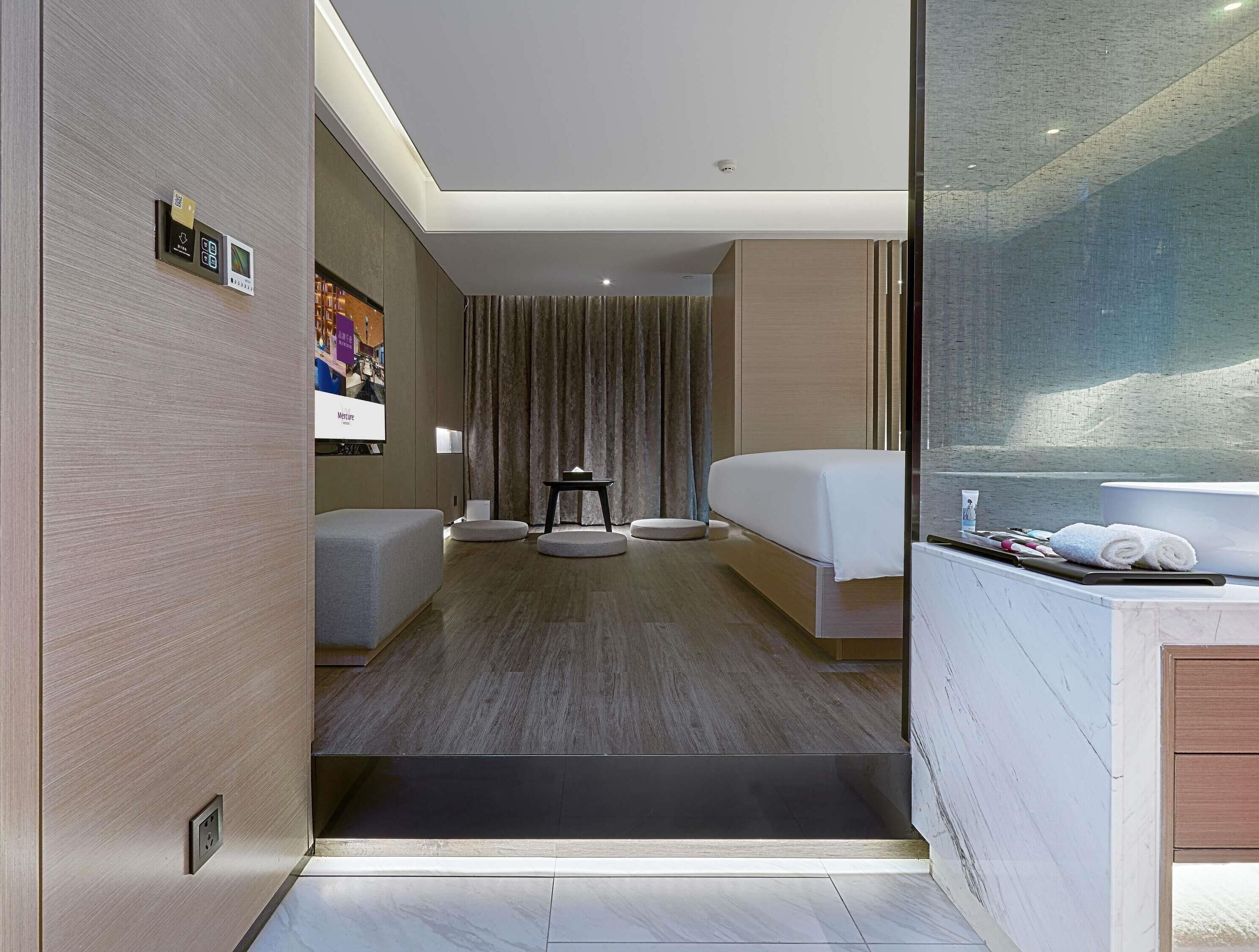 Ein modernes Hotelzimmer mit einem Bett, einem kleinen Tisch, einer Sitzecke und einem Badezimmer mit einer Badewanne.