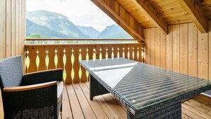 En träveranda med ett bord och stolar, med utsikt över ett bergigt landskap.