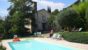 A swimming pool with lounge chairs and an inflatable float. - Holiday Home in Ardeche Near Chateau de Ventadour (Lalevade-d'Ardeche)
