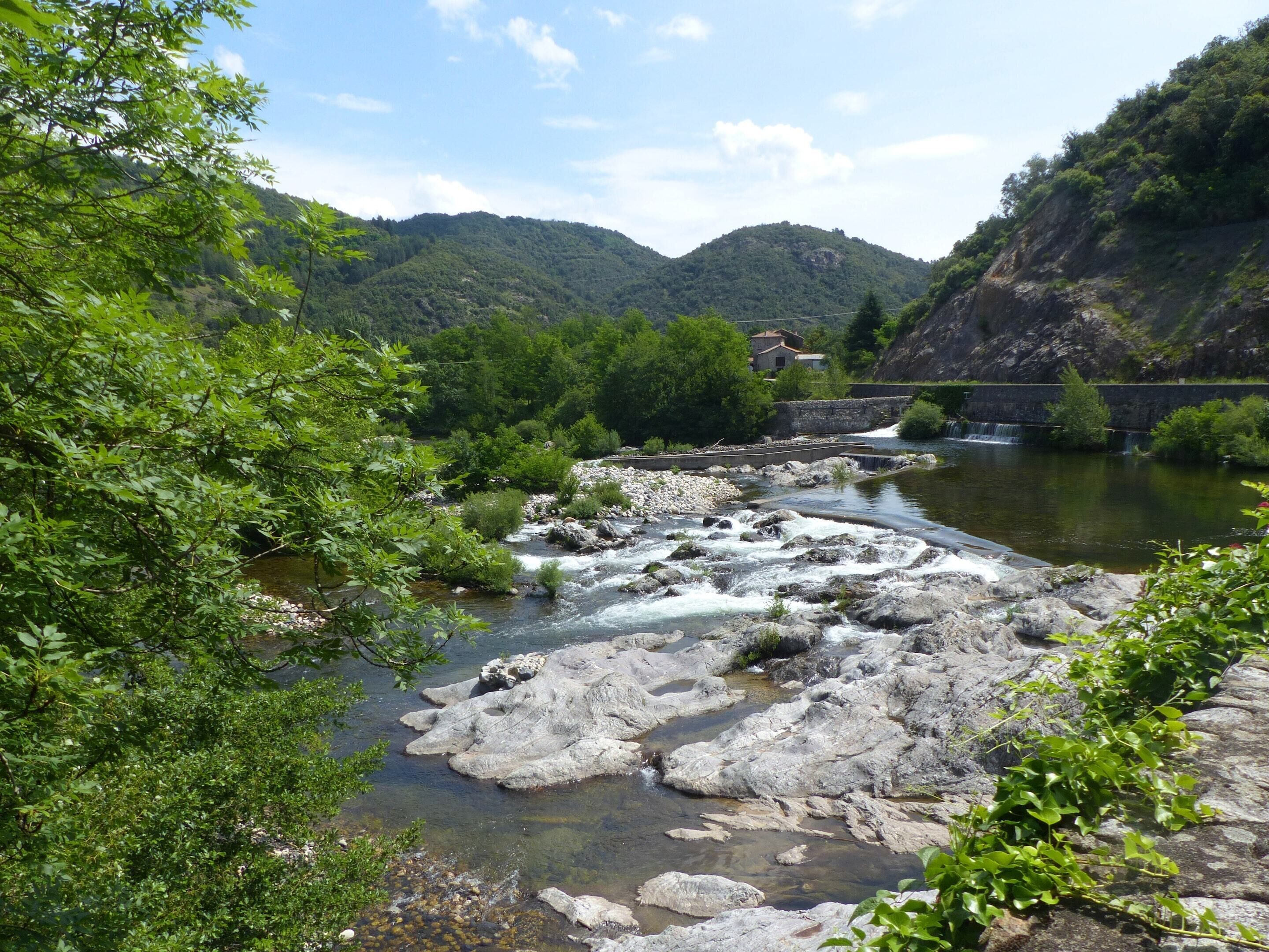 Un río serpentea por un valle con terreno rocoso y vegetación.