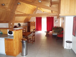 Ein geräumiger Loft mit hohen Decken, einer Küchenzeile, einem Esstisch und einer gemütlichen Sitzecke.