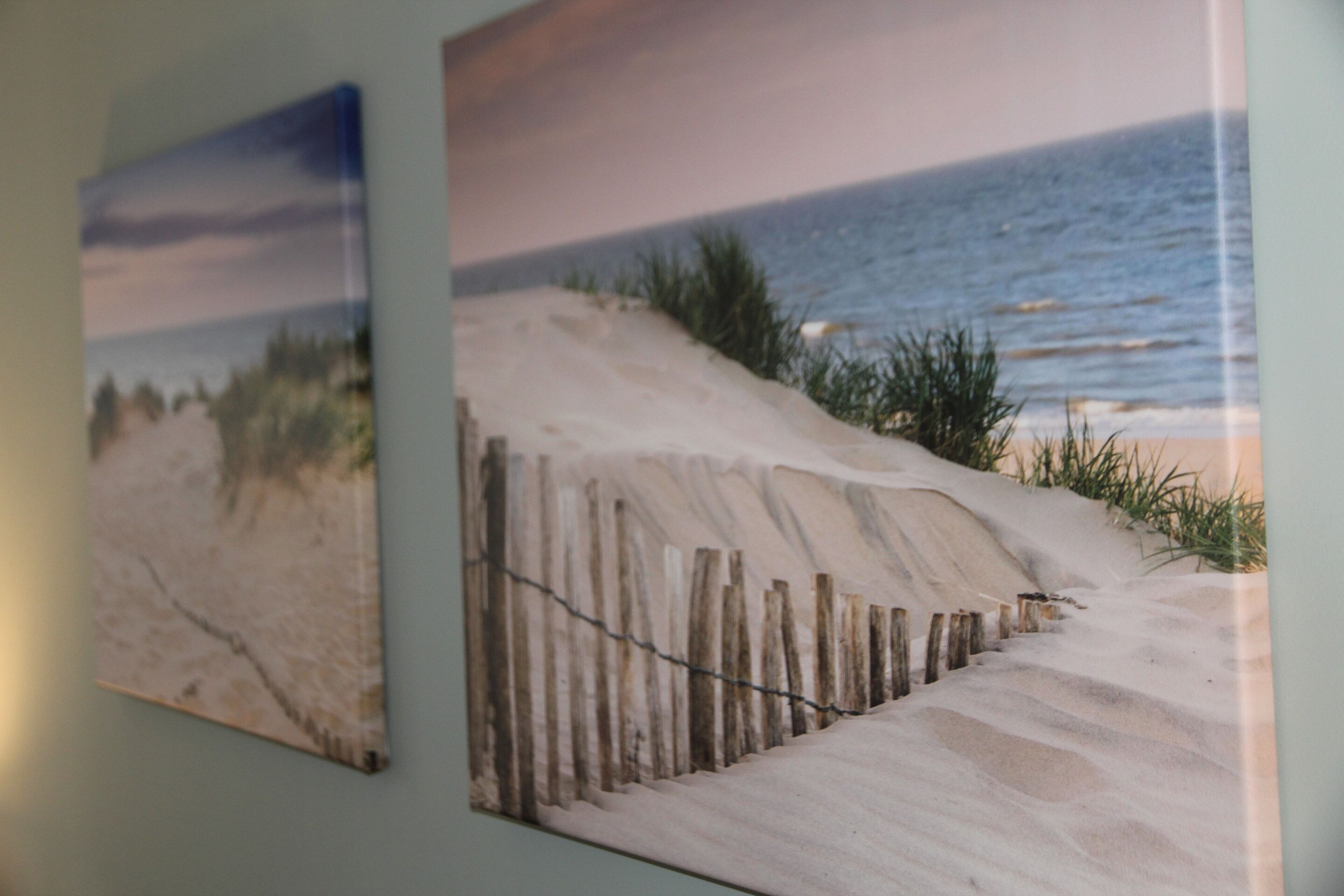 En vägg med två inramade konstverk som föreställer strandscener.