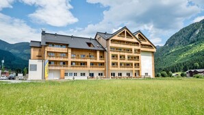 Un immeuble en bois à plusieurs étages, doté de balcons, qui se dresse sur un fond de paysage montagneux.