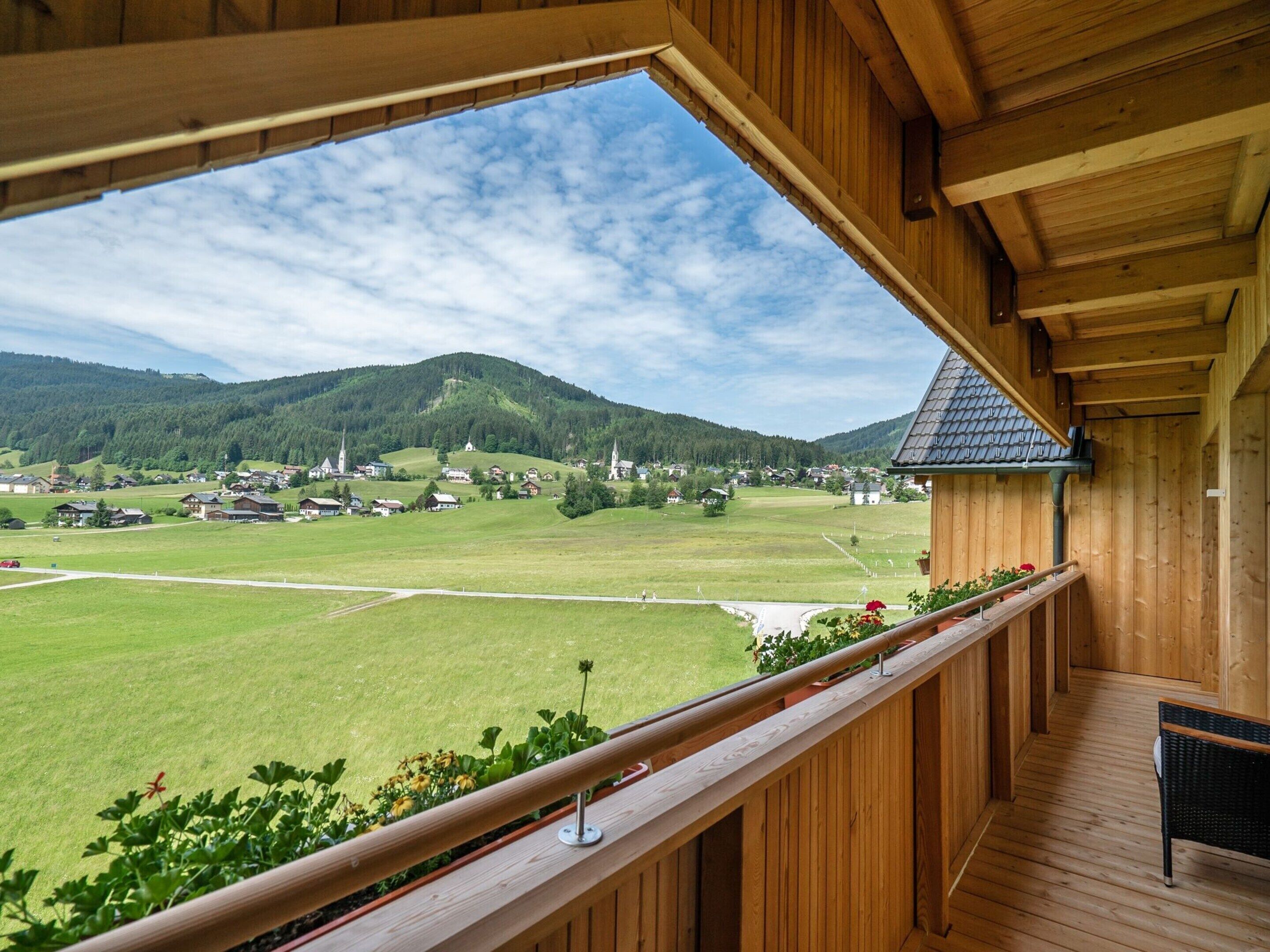 Ein Holzbalkon mit Blick auf ein grünes Feld und eine Kirche in der Ferne.