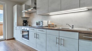 Une cuisine moderne avec des meubles gris, des appareils en acier inoxydable et une grande fenêtre.