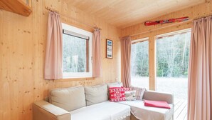 A cozy cabin interior with a beige sofa, a small armchair, and a window with curtains. - Chalet in Stadl an der Mur / Styria With Terrace (Stadl-Predlitz)