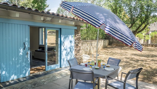 A patio with a table, chairs, and a striped umbrella. - Cottage With River Views, Uzer (Uzer)