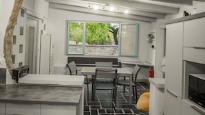 A modern kitchen with a dining area, a stone wall, and a window with a view of greenery. - Cottage With River Views, Uzer (Uzer)