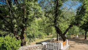 A park with a stone wall, a wooden bench, and a white picket fence. - Cottage With River Views, Uzer (Uzer)