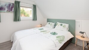 A bedroom with a bed, a nightstand, a lamp, and a window with curtains. - Quaint Apartment in Schoorl near Tennis Court (Schoorl)