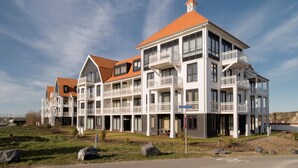 A multi-story hotel with balconies, a red roof, and a clear sky. - Luxurious Penthouse With 3 Bathrooms, Near the Sea (Cadzand-Bad)