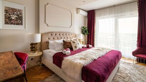 Ein Schlafzimmer mit einem großen Bett, einem roten Sessel, einem kleinen Tisch und einer Pflanze.