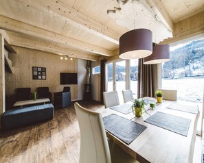 A modern interior with a wooden ceiling, a dining area with a large table and chairs, a sofa, and a fireplace. - Pleasant Chalet With Whirlpool (Sankt Georgen am Kreischberg)