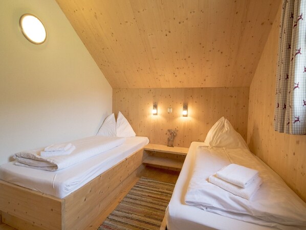 Une pièce chaleureuse avec deux lits superposés en bois, une petite table et un luminaire fixé au mur.